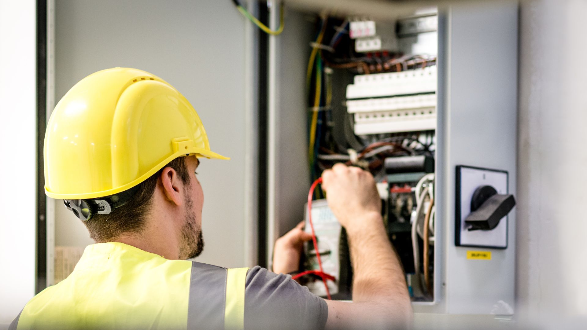 A man in a hard hat working on an electrical panel